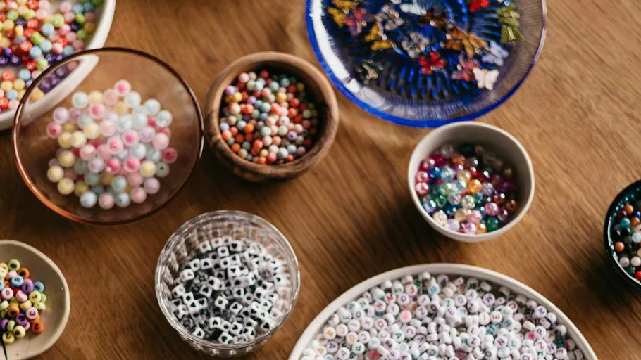 Assorted beads in bowls on wooden table.