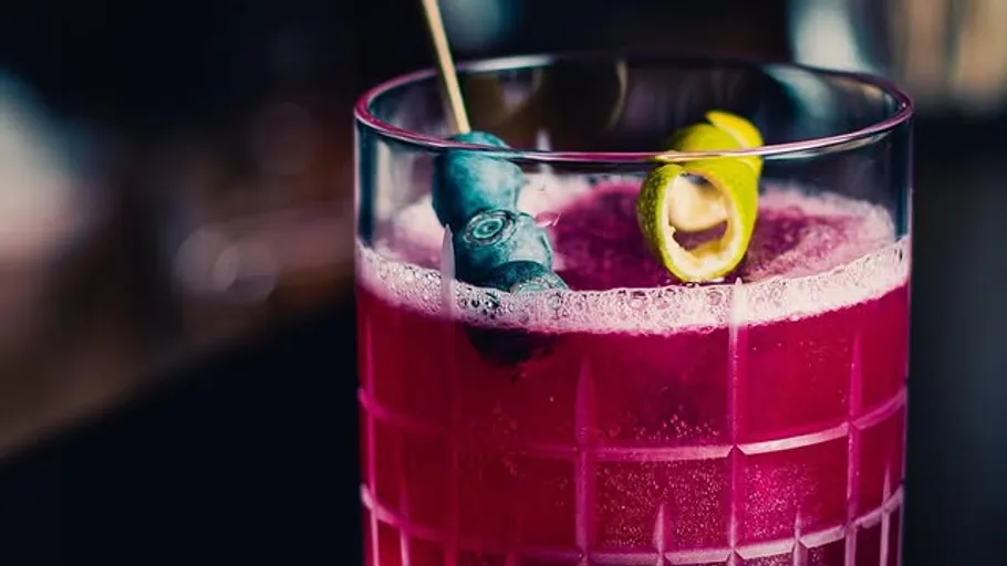 Lila Cocktail mit Garnitur im Glas.