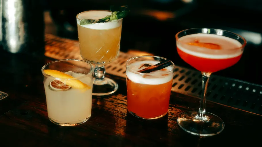 Four cocktails on a dimly lit bar.