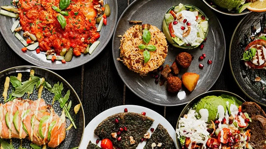 Various dishes on dark plates with garnishes.