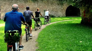 Cyclists riding towards a brick tunnel outdoors.