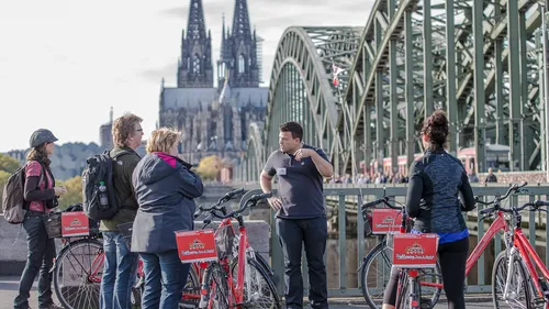 Group with bikes on bridge near cathedral.