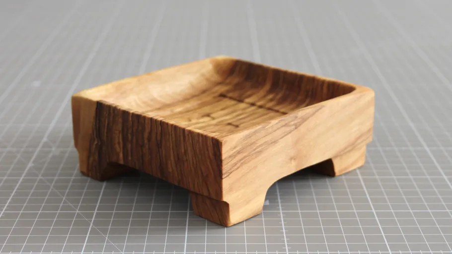 Wooden soap dish on grid-patterned surface.