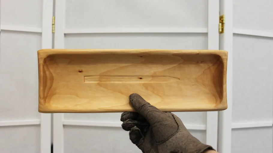 Hand holding rectangular wooden tray indoors.