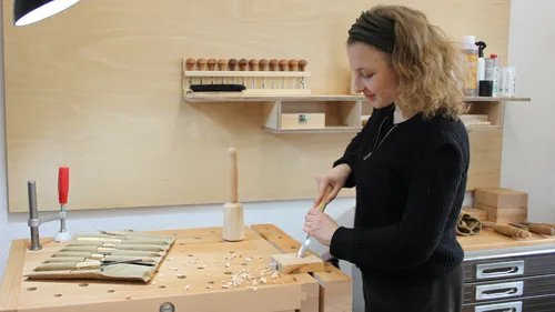 Person carving wood in a workshop.