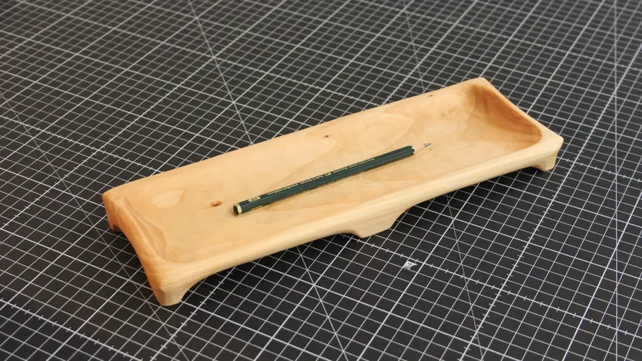 Holztablett mit Bleistift auf kariertem Untergrund.