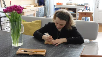 Person wood carving at a craft table.