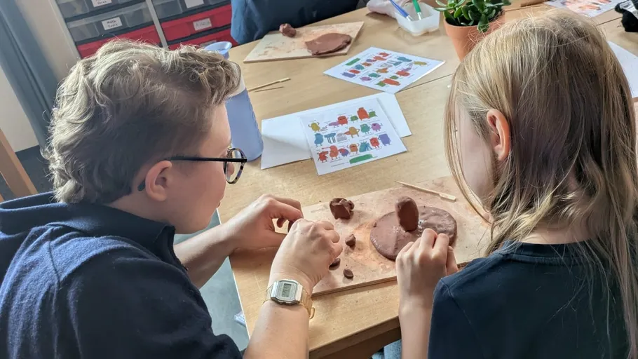 Children molding clay at a table.
