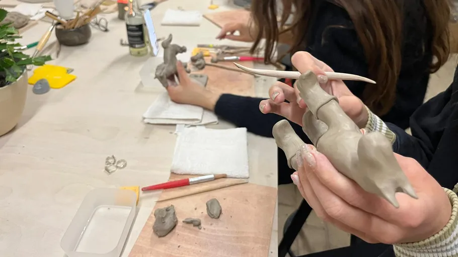 People molding clay sculptures on a table.