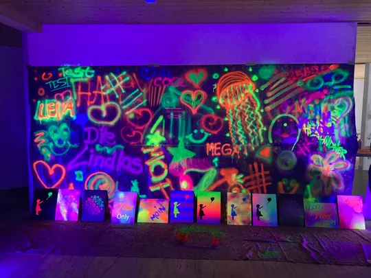 Neon-Graffiti an Wand unter UV-Licht.