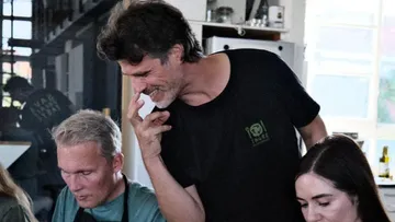 Mann lächelt, interagiert mit Menschen in einer Küche.