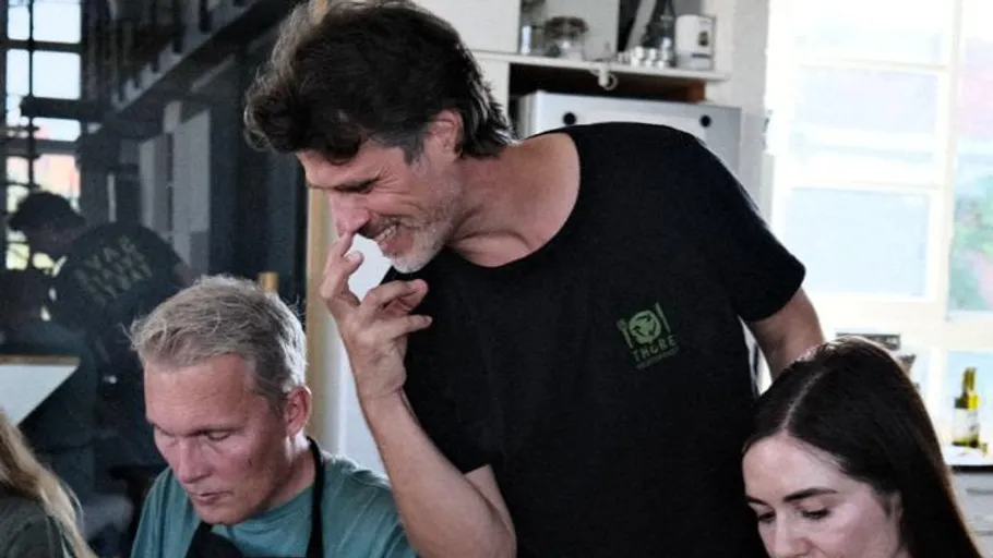 Mann lächelt, interagiert mit Menschen in einer Küche.