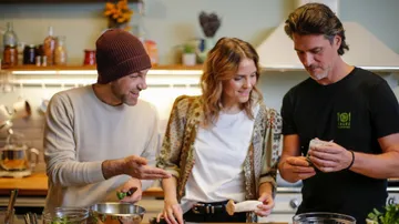 Drei Personen kochen zusammen in Küche.