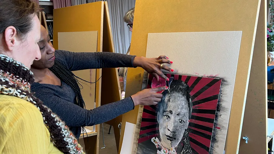 Zwei Frauen betrachten Mixed-Media-Kunst im Studio.