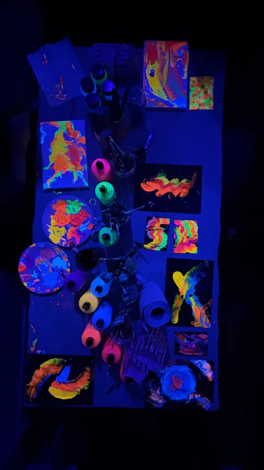 Glowing neon paints and artwork on table.