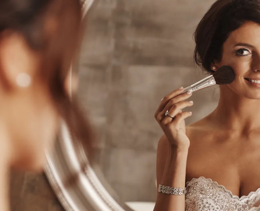 Woman applying makeup in front of mirror.