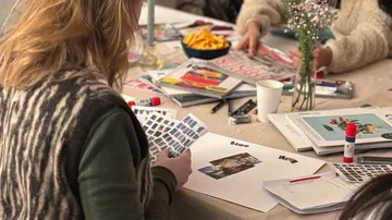 Person crafting with photos at a table.