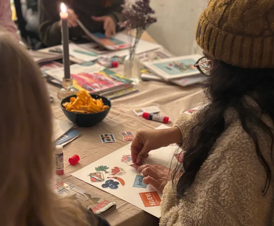 Woman crafting at a table with collage materials.