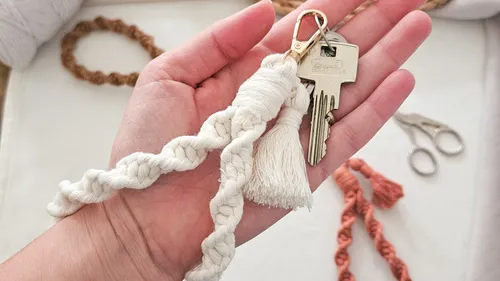 Hand holding macrame keychain with keys.