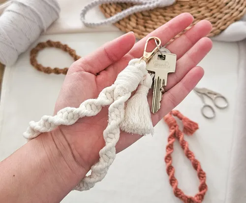 Hand hält Makramee-Schlüsselanhänger mit Schlüsseln.