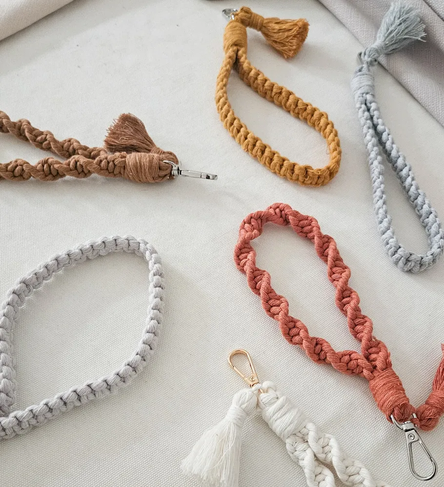 Colorful macramé keychains on white fabric.