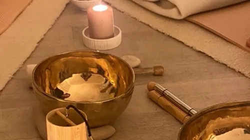 Meditationsecke mit Schalen und Kerze beleuchtet.