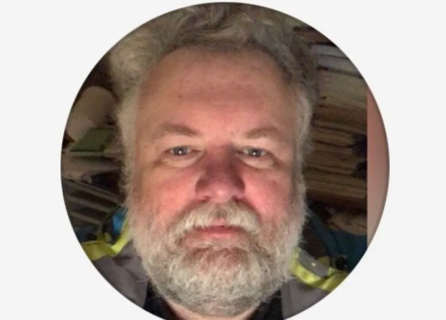 Bearded man with books in background.