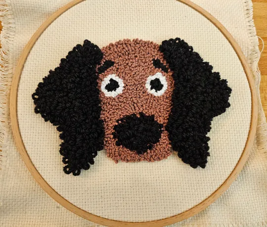 Punch-Needle-Hundegesicht auf Stickrahmen.