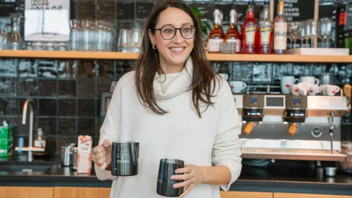 Frau hält Tassen in einem Café.