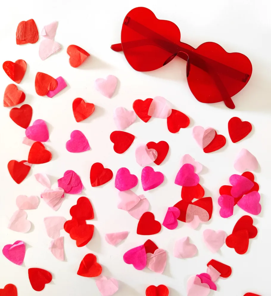 Herzsonnenbrille mit Konfetti auf weißem Hintergrund.