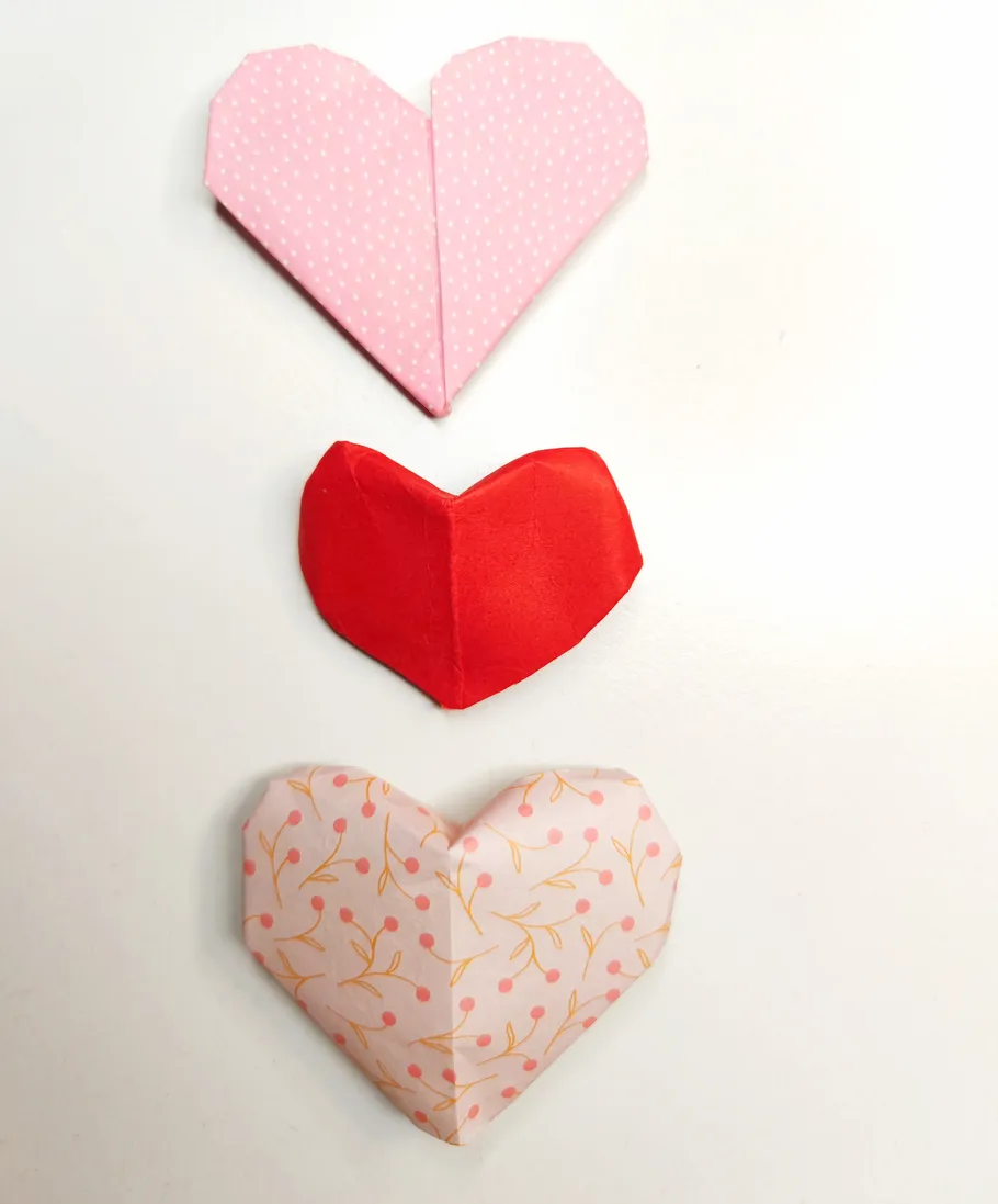 Drei Origami-Herzen auf weißem Hintergrund.
