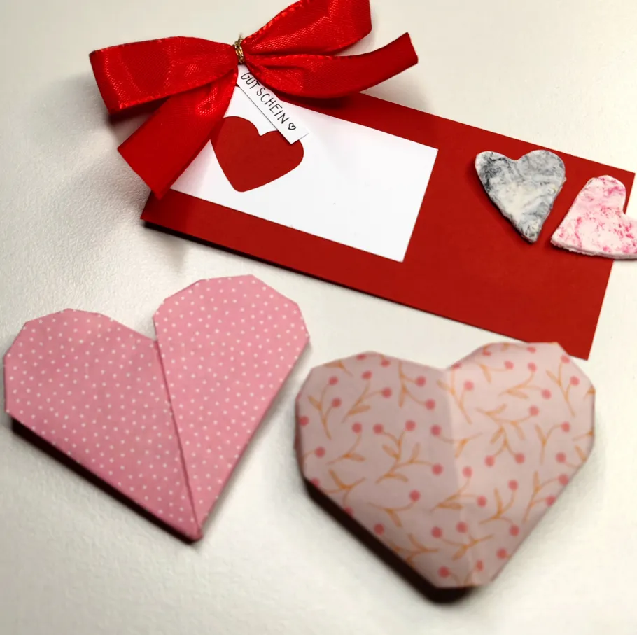 Origami-Herzen und Geschenkkarte auf Tisch.