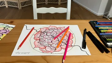 Colored mandala drawing with pencils on a table.
