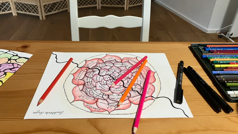 Buntes Mandala-Zeichnen mit Stiften auf einem Tisch.