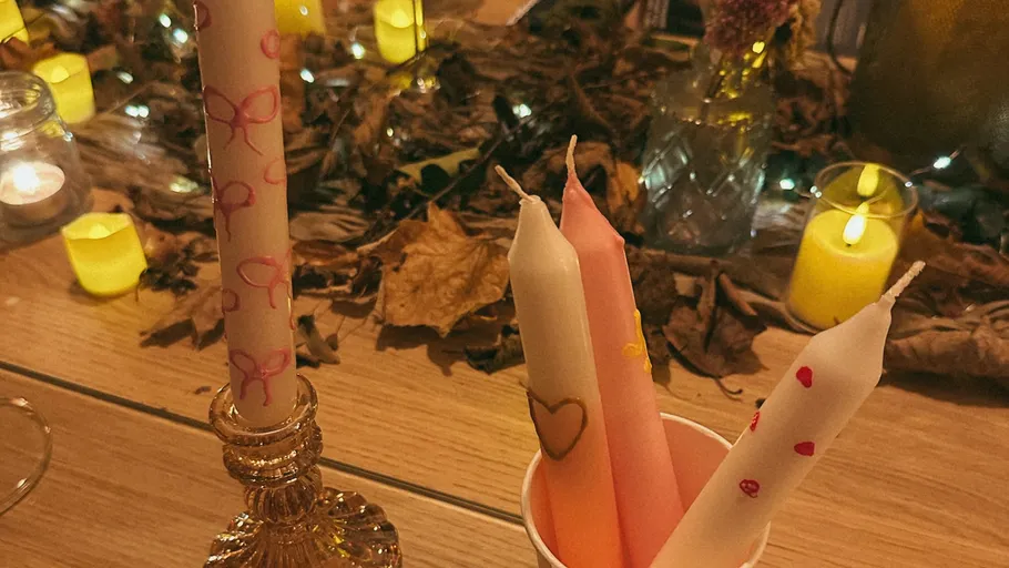 Decorated candles on table with leaves.