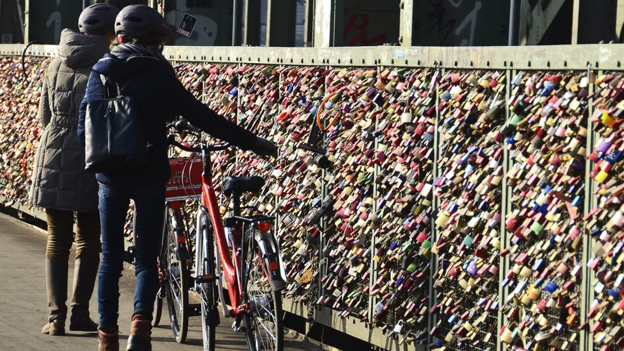 Cyclists walking by bridge full of locks.