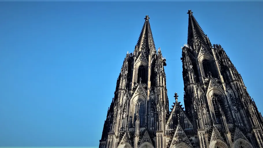 Two Gothic cathedral towers against blue sky.
