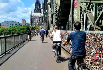 Cyclists riding on bridge, cathedral in background.