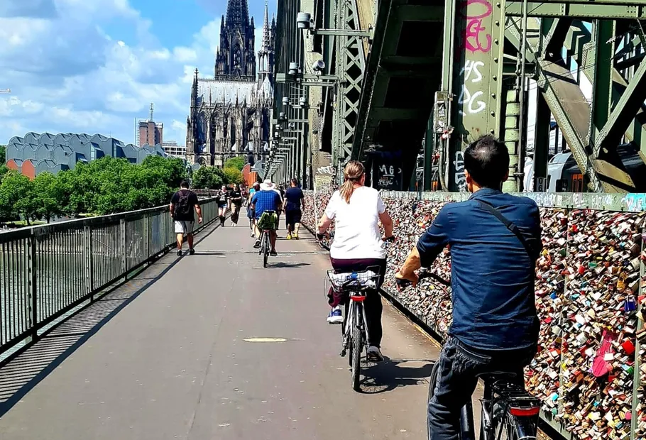 Radfahrer fahren auf Brücke, Kathedrale im Hintergrund.