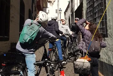 Group of cyclists looking upwards in narrow alley.