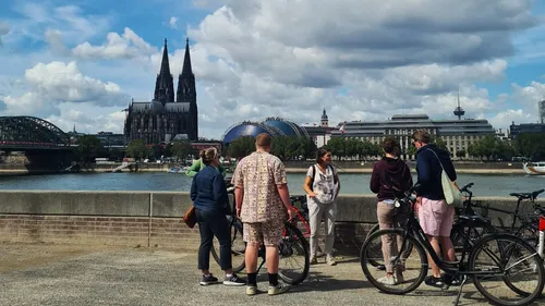 Personen mit Fahrrädern blicken auf Kölner Dom.