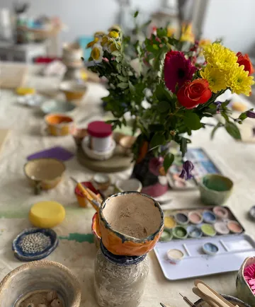 Keramikschalen und Blumen auf Kunsttisch.