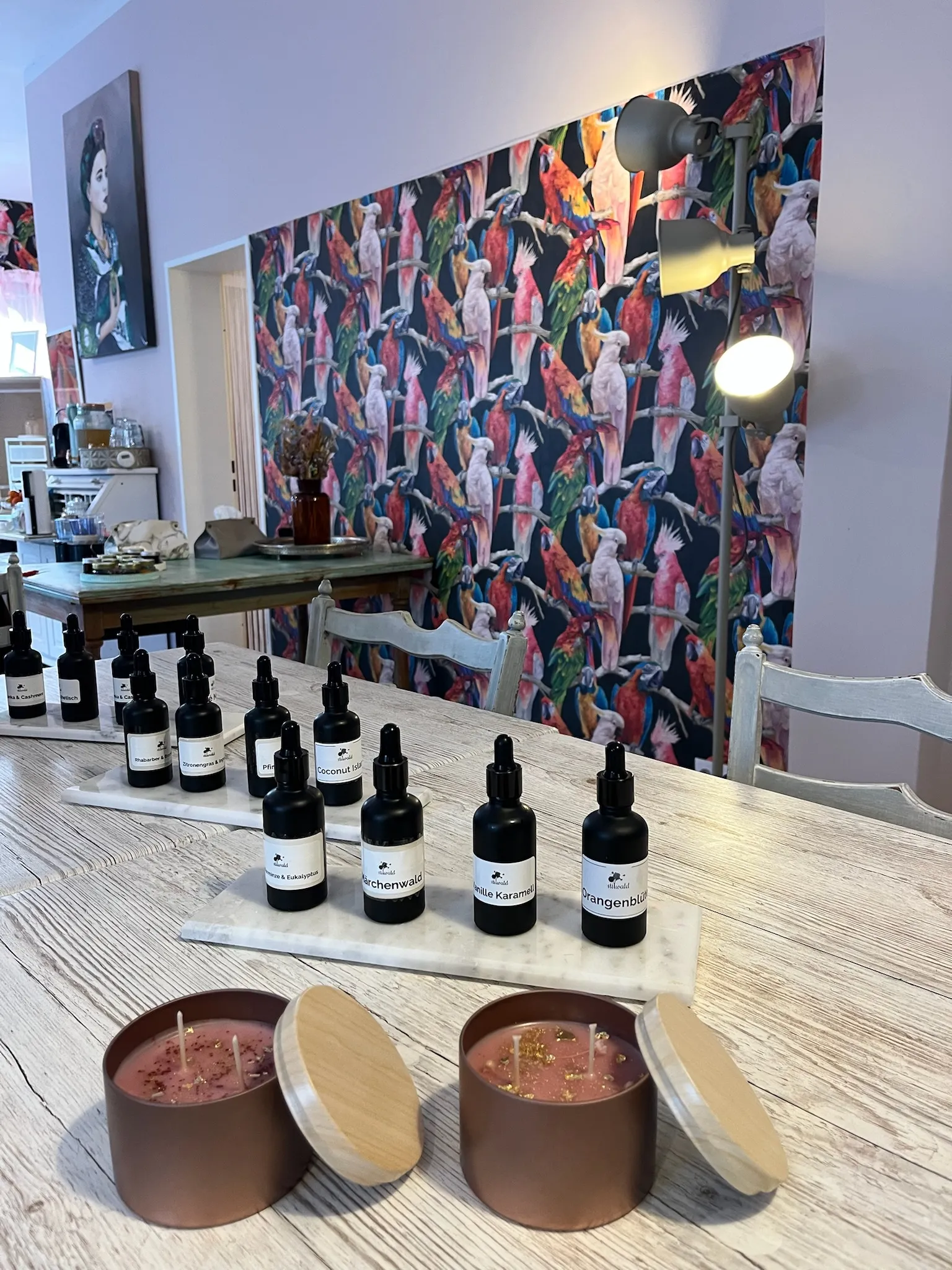 Aromaflaschen auf Holztisch, bunte Vogel-Tapete.