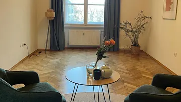 Wohnzimmer mit Stühlen und rundem Tisch.