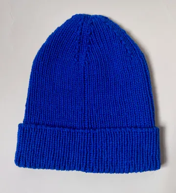 Blue knit beanie on white background.