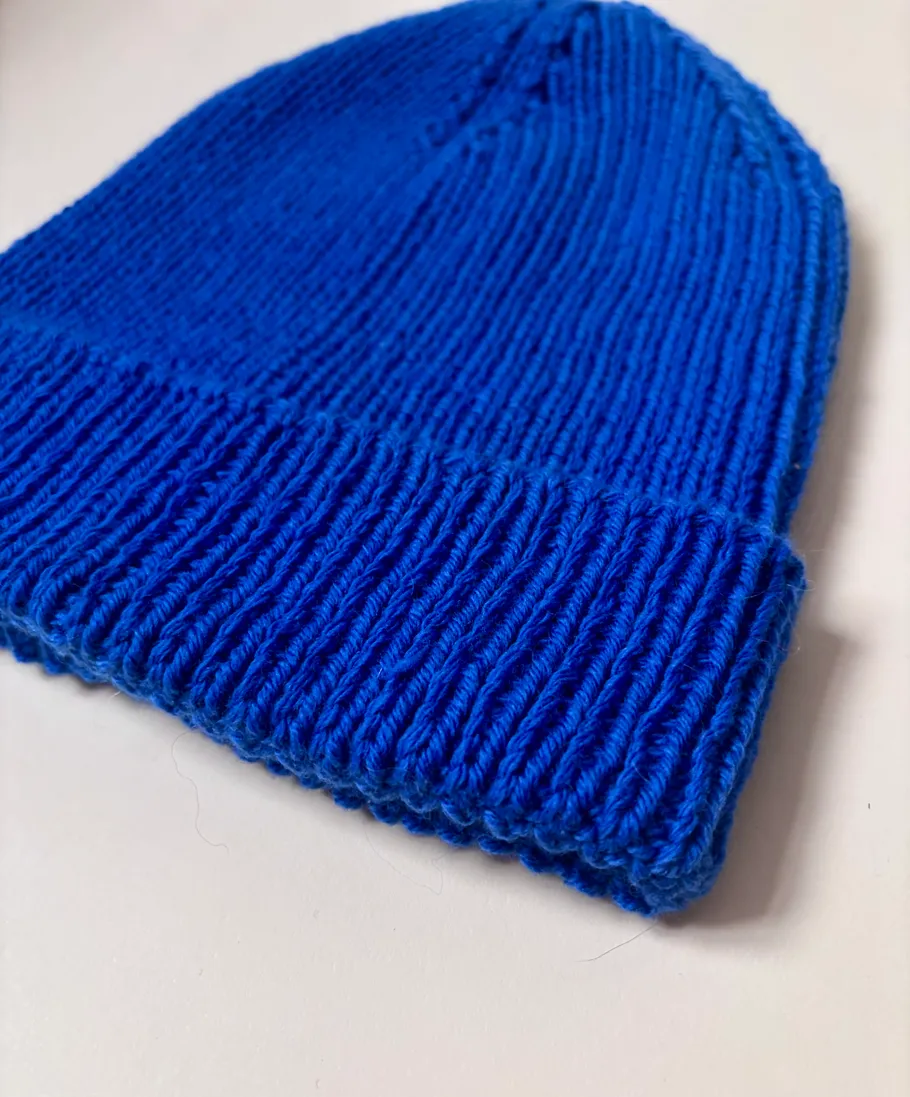 Blaue Strickmütze auf weißer Fläche.