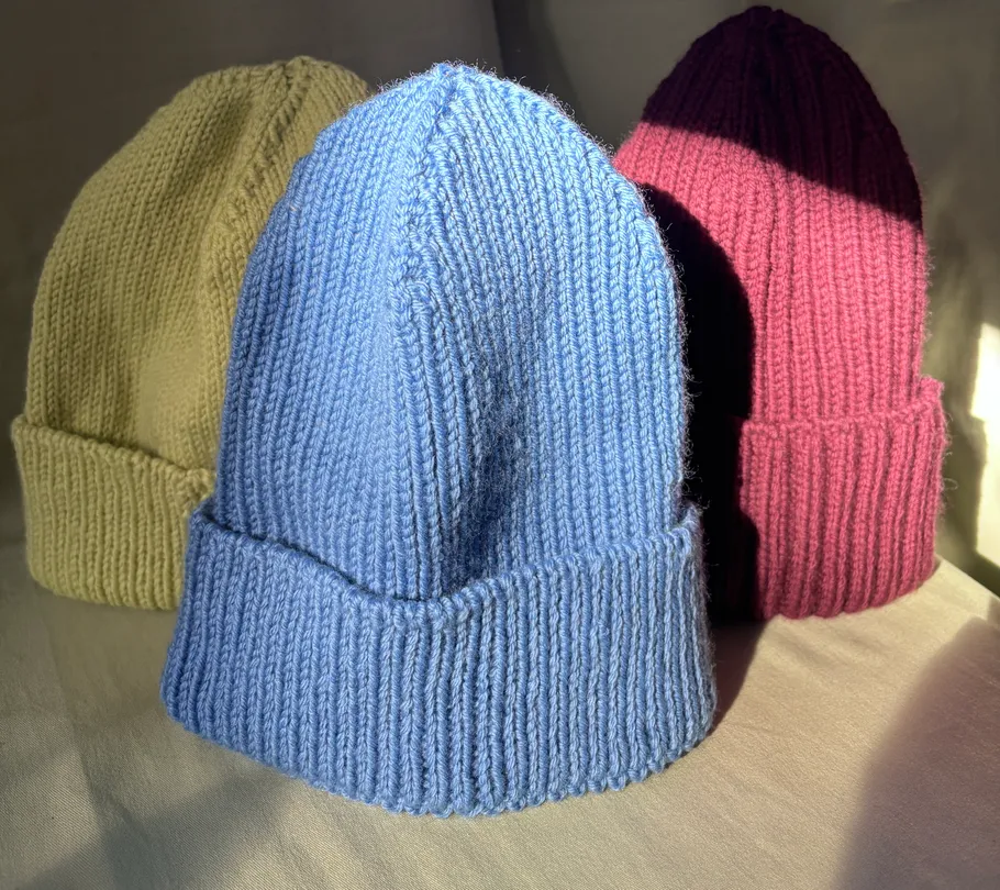Drei gestrickte Mützen in verschiedenen Farben.