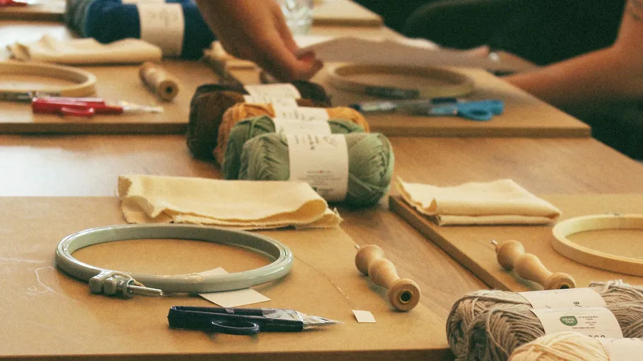 Embroidery supplies on table, people crafting.