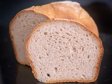 Schnelles Brot, in zwei dünne Scheiben geschnitten, auf Tisch.