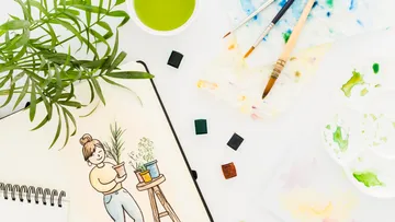 Painting supplies and plant illustration on table.